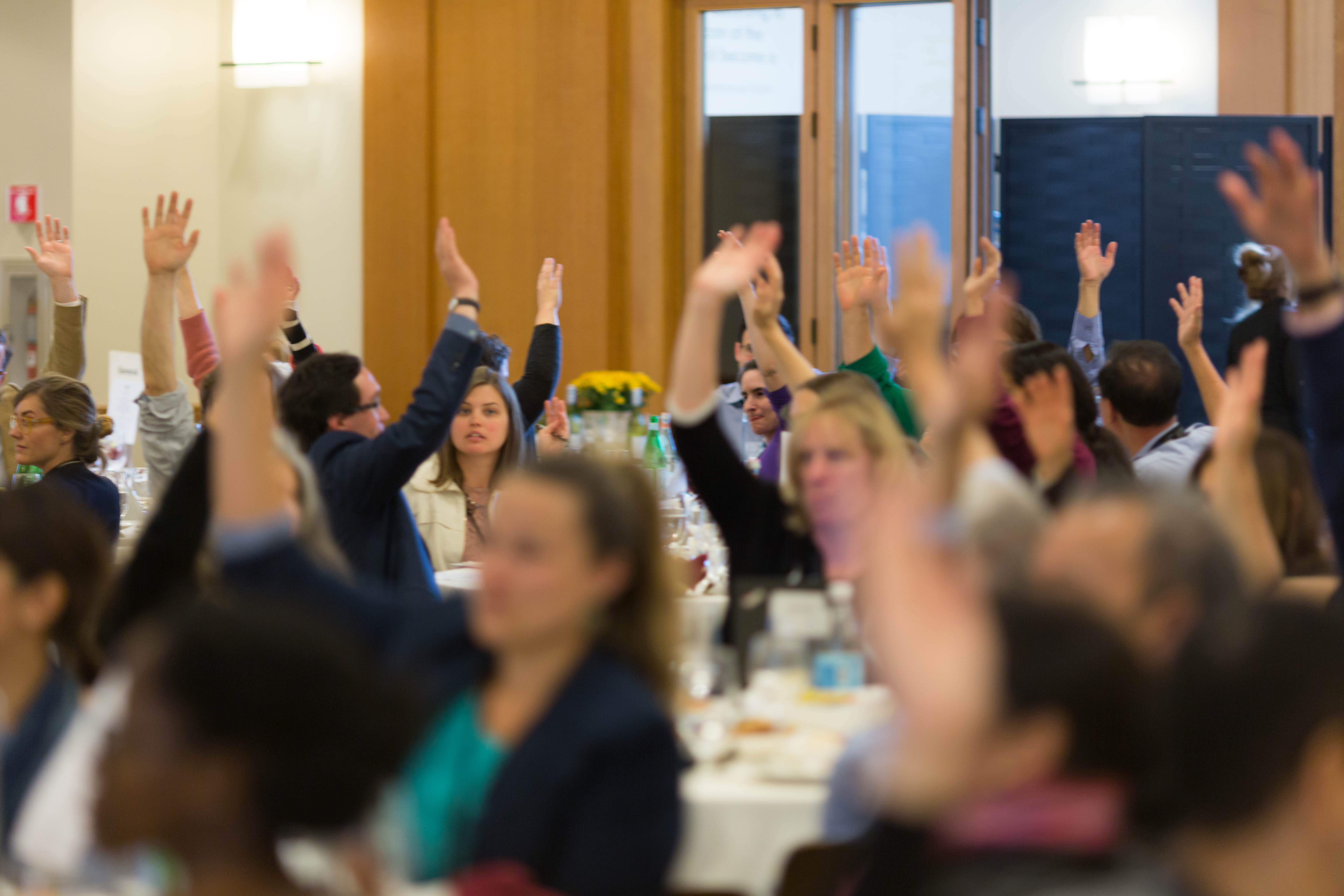 Conference attendees raise their hands during morning plenary activity