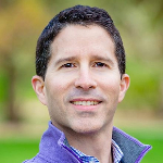 Mitch Weiss smiling wearing a purple collared shirt