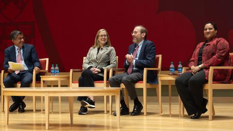 Harvard educators sitting on a well lit stage at HBS