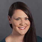 Kerry Foley smiling brightly in front of a gray backdrop.