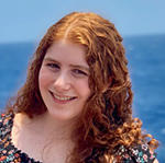 Julia Losner smiling in front of an ocean front view.