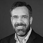 Timothy O’Brien's headshot in black and white as he smiles brightly at the camera.