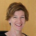 Kristin Lofblad Sullivan smiling brightly in front of a yellow gold backdrop.