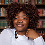 Najya Williams smiling in front of a colorful bookcase.