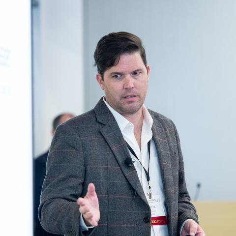 HILT 2025 Conference Speaker wearing a white button down shirt under a striped gray blazer.