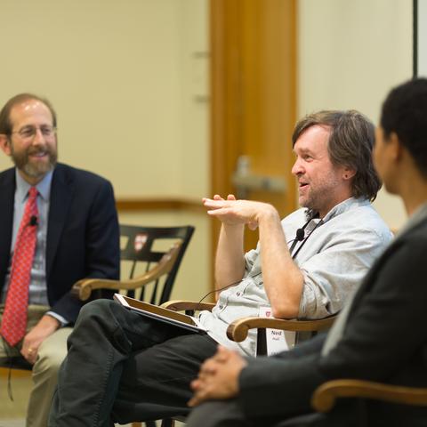 HILT Conference panelists on stage with three wooden Harvard chairs.