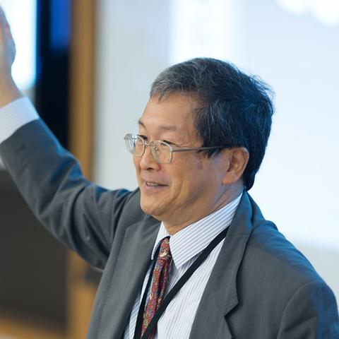 A man with black and gray hair wearing clear glasses and a white button up shirt.