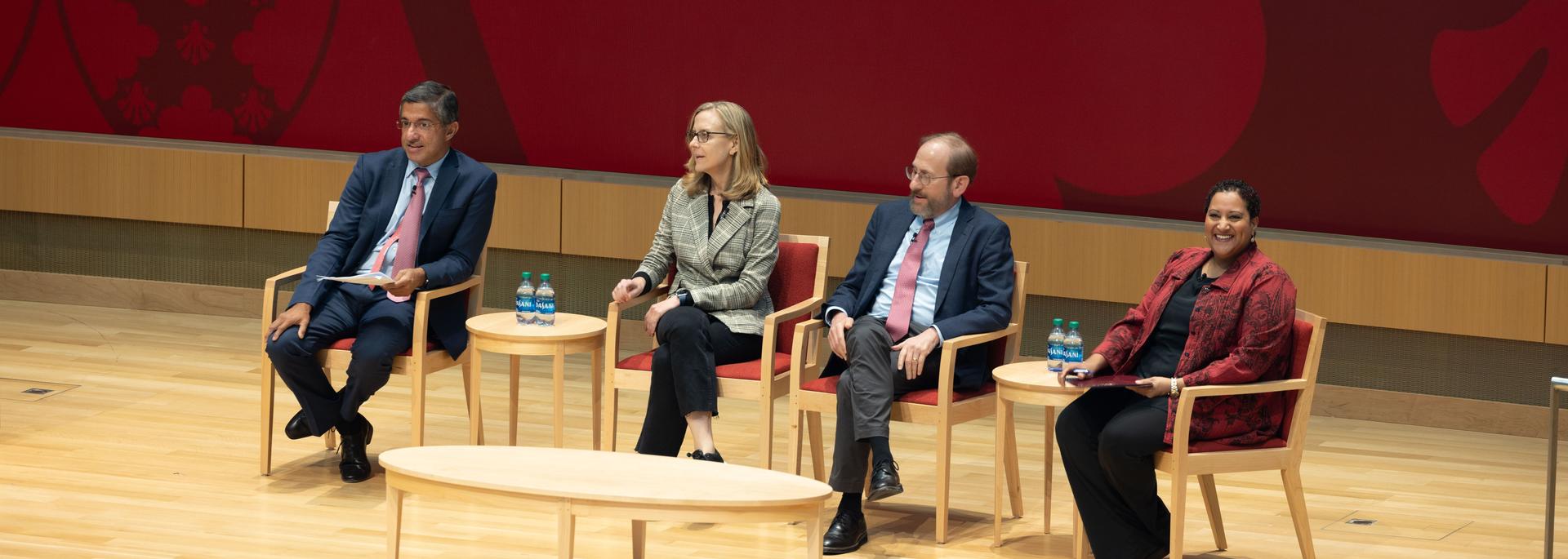 A group of Harvard educators on stage sitting in red and tan chairs
