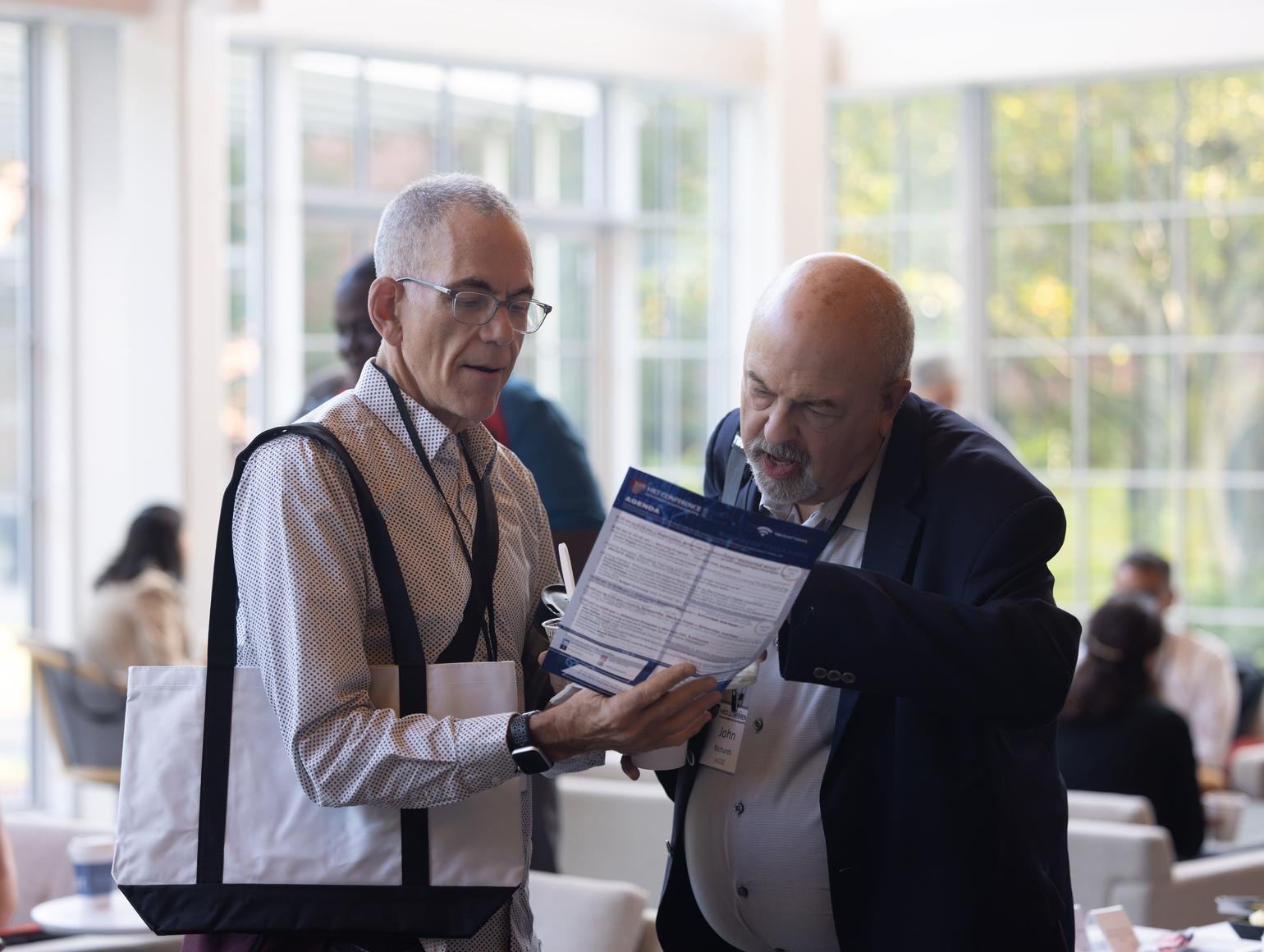 Two people reading the 2023 HILT conference program