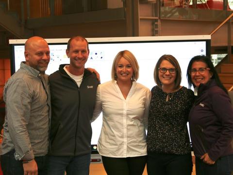 Group of educators posing in front of white board.