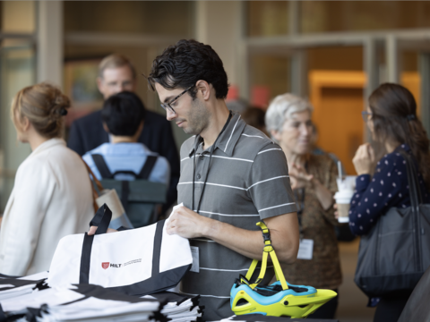 A man holding up a HILT conference tote bag