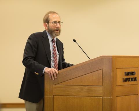 Allan Garber speaking into a microphone at a wooden podium.