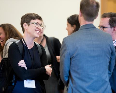 A woman with short brown hair networking with her colleagues.