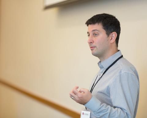 A man with black hair wearing a blue long sleeve button up.