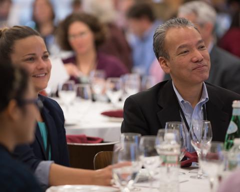 HILT Conference attendees sitting at a table with wine glasses, food, and water bottles.