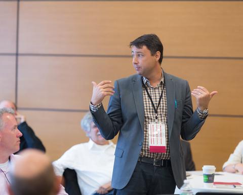 A man with shortbrown hair wearing a gray blazer and a HILT Conference name tag.