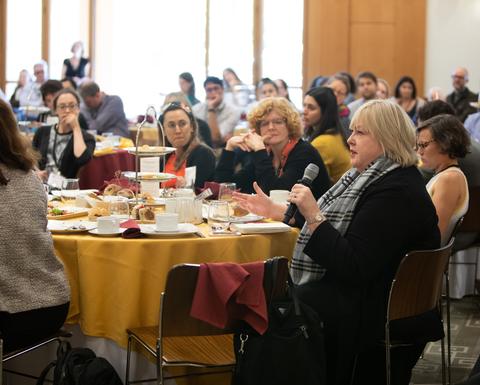 People sitting at round tables with yellow table cloth