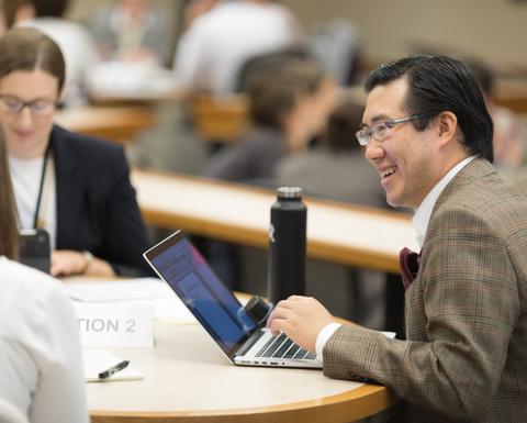 An educator using his medium sized silver laptop.
