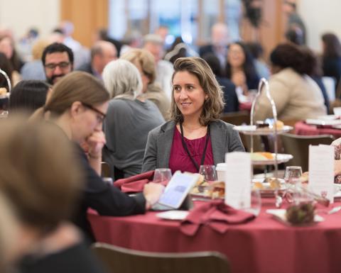HILT Conference attendees sitting at a round table that has red table cloth and an assortment of small bites.