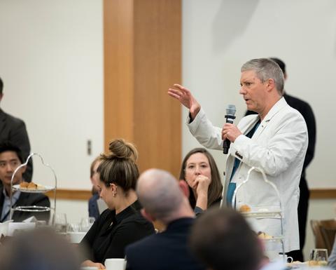 A tall man with gray hair wearing a white blazer.