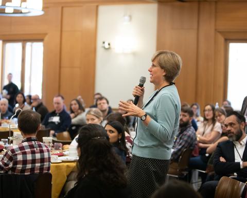 A woman in a green sweater speaking into a microphone