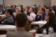 Attendees listen to speakers during morning plenary
