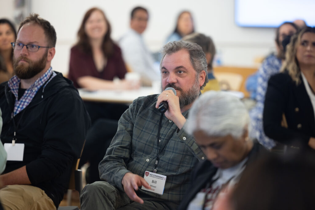 An audience member engaging in conversation with their peers during the breakout session "Harvard Generative AI Tools: Demo and Discussion"