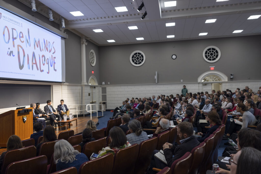 A lecture hall with red chairs, people, and circle shaped windows